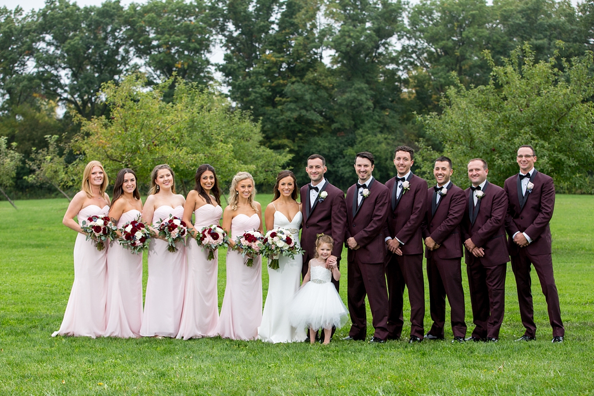 chantelle marie lakehouse and celebration venue, sarah heppell photography, wedding party with flower girl, bridesmaids in blush pink dresses, groomsmen in maroon suits and black ties, whistlestop florist bouquets, wedding bouquets with maroon dahlias, white roses, and blue berries