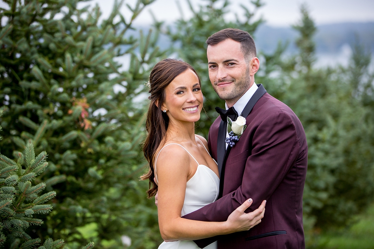 chantelle marie lakehouse and celebration venue, sarah heppell photography, bride and groom on owasco lake, groom in maroon suit with black tie, white rose boutonnière, 