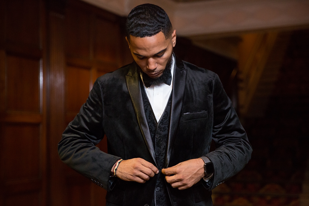 groom buttons black velvet suit jacket from men's wearhouse while getting ready at the landmark theatre, sarah heppell photography